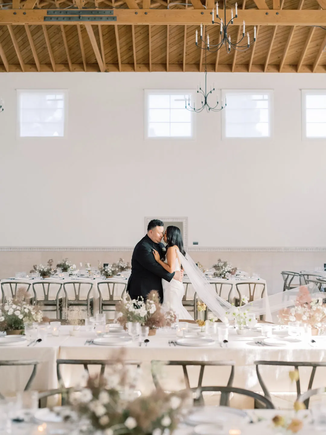 Bride and groom kissing behind a reception dining table