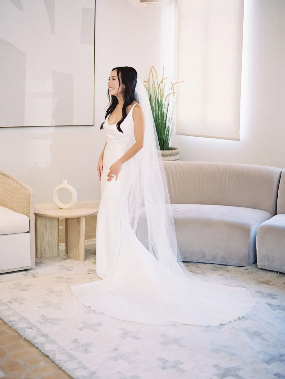 Bride standing beside a curved dressing-room sofa