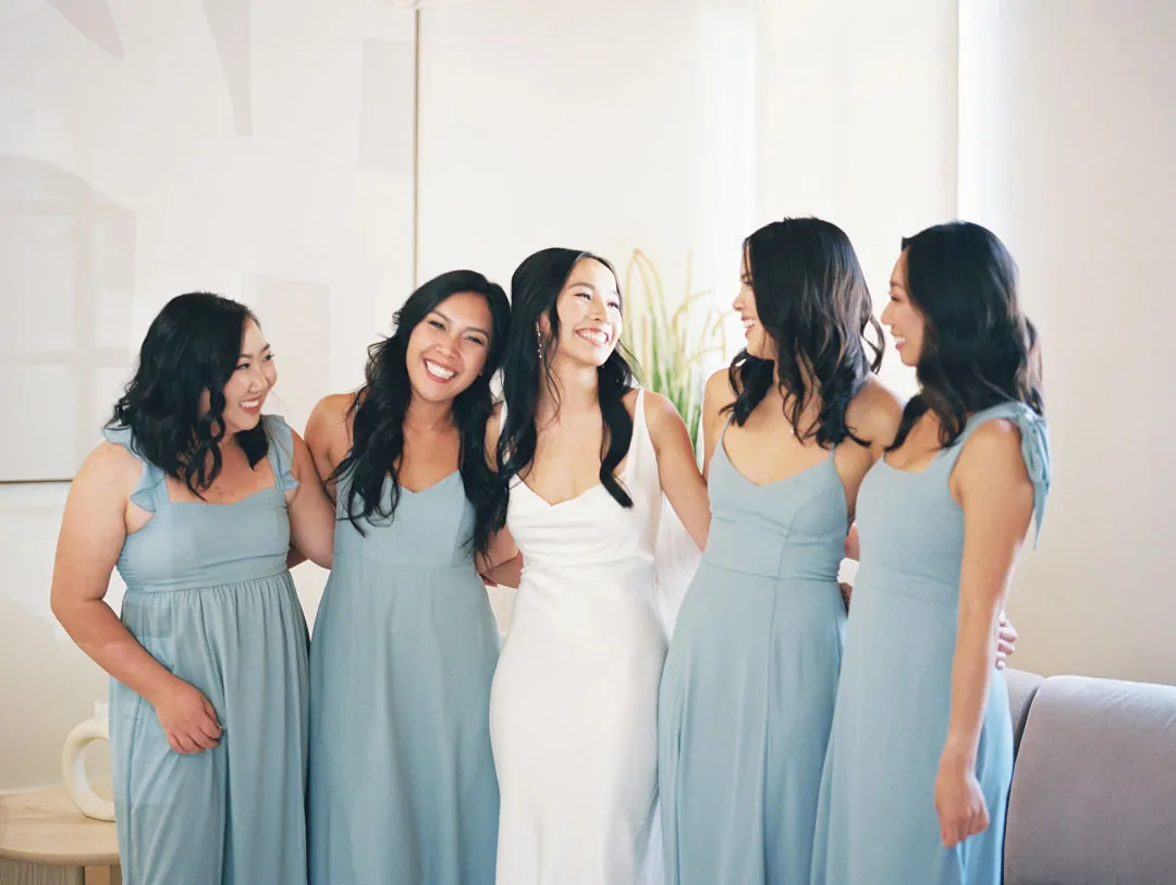 Bride and bridesmaids smiling together while getting ready
