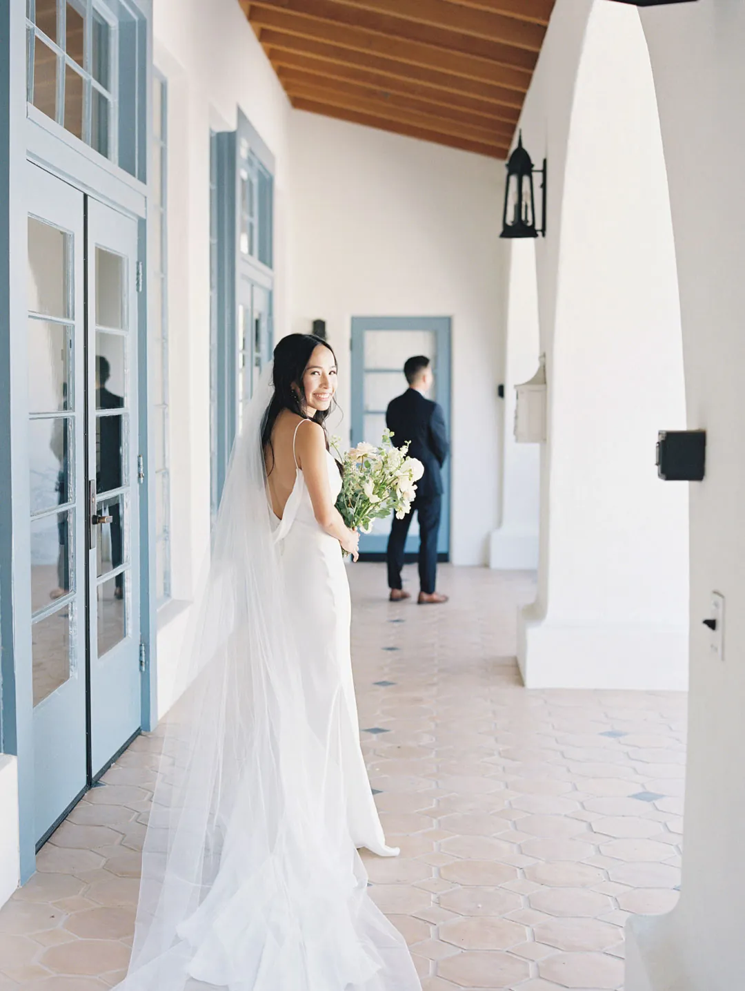 Bride holding her bouquet outside glass doors