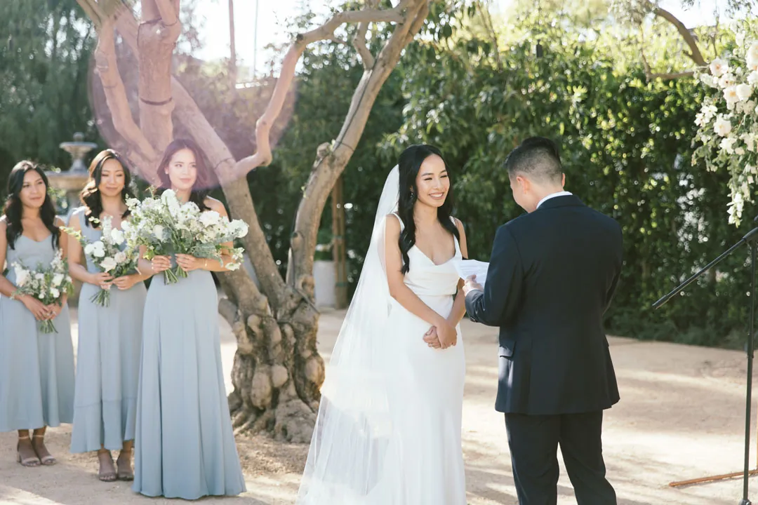 Bride holding the groom's hands beside her bridesmaids