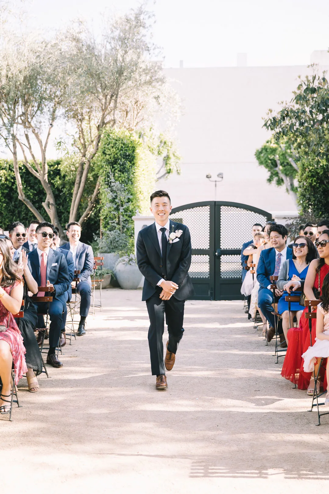 Groom walking down the courtyard ceremony aisle