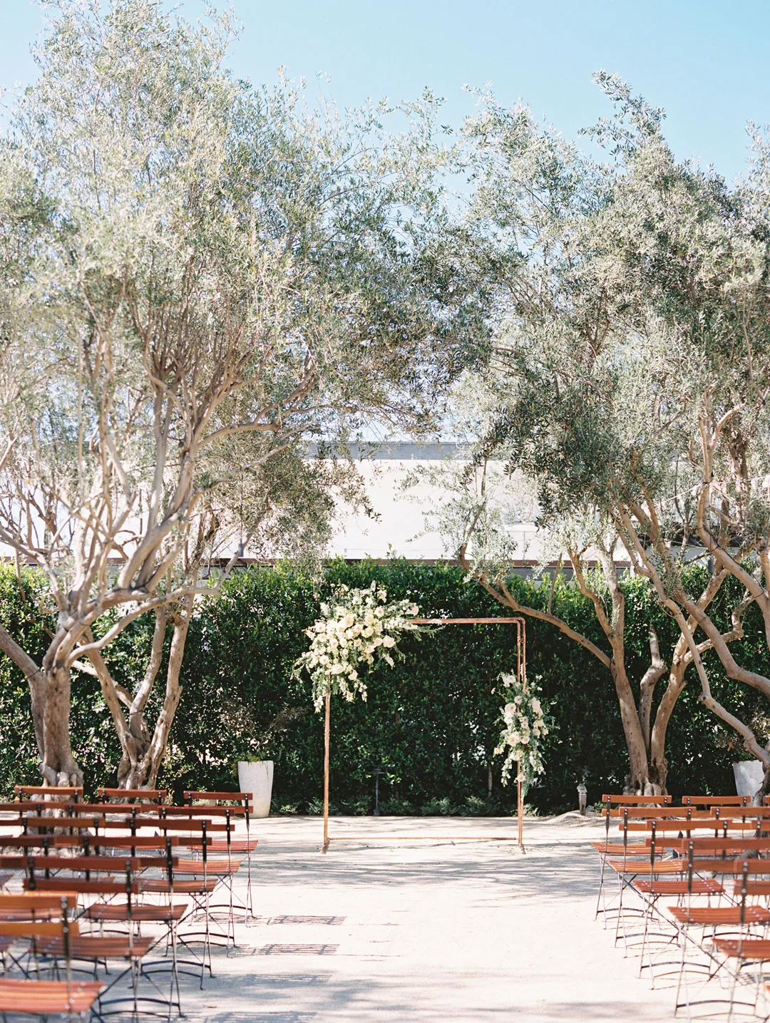 Courtyard ceremony aisle facing a white floral arch