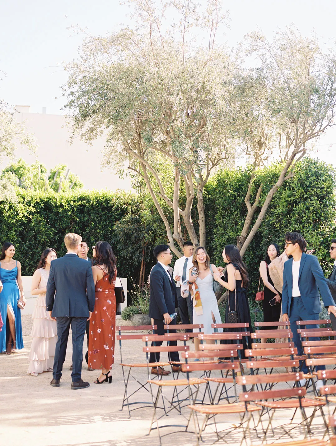 Guests standing among outdoor ceremony chairs