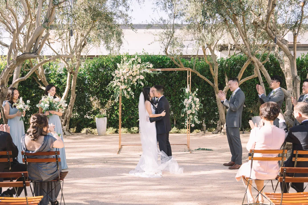 Bride and groom embracing in a courtyard ceremony aisle