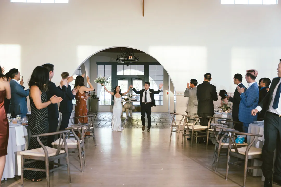 Newlyweds entering the reception hall between standing guests