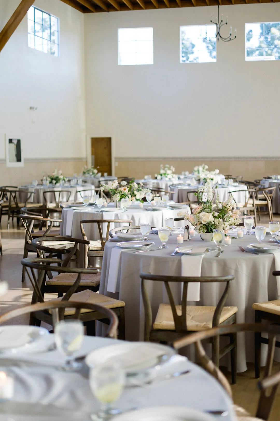 Dining tables with white linens, glassware, and floral centerpieces
