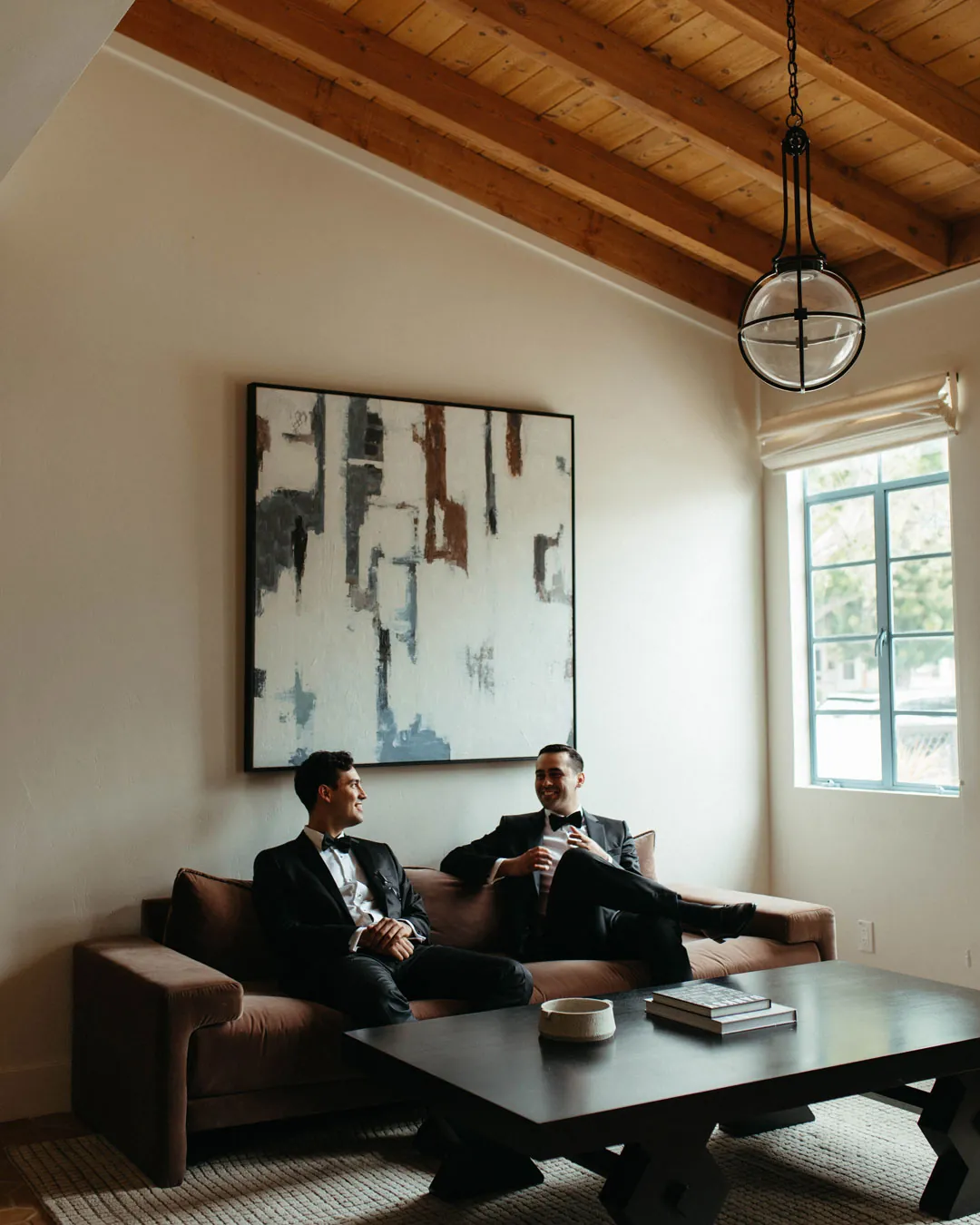 The groom and a friend relax on lounge sofas.