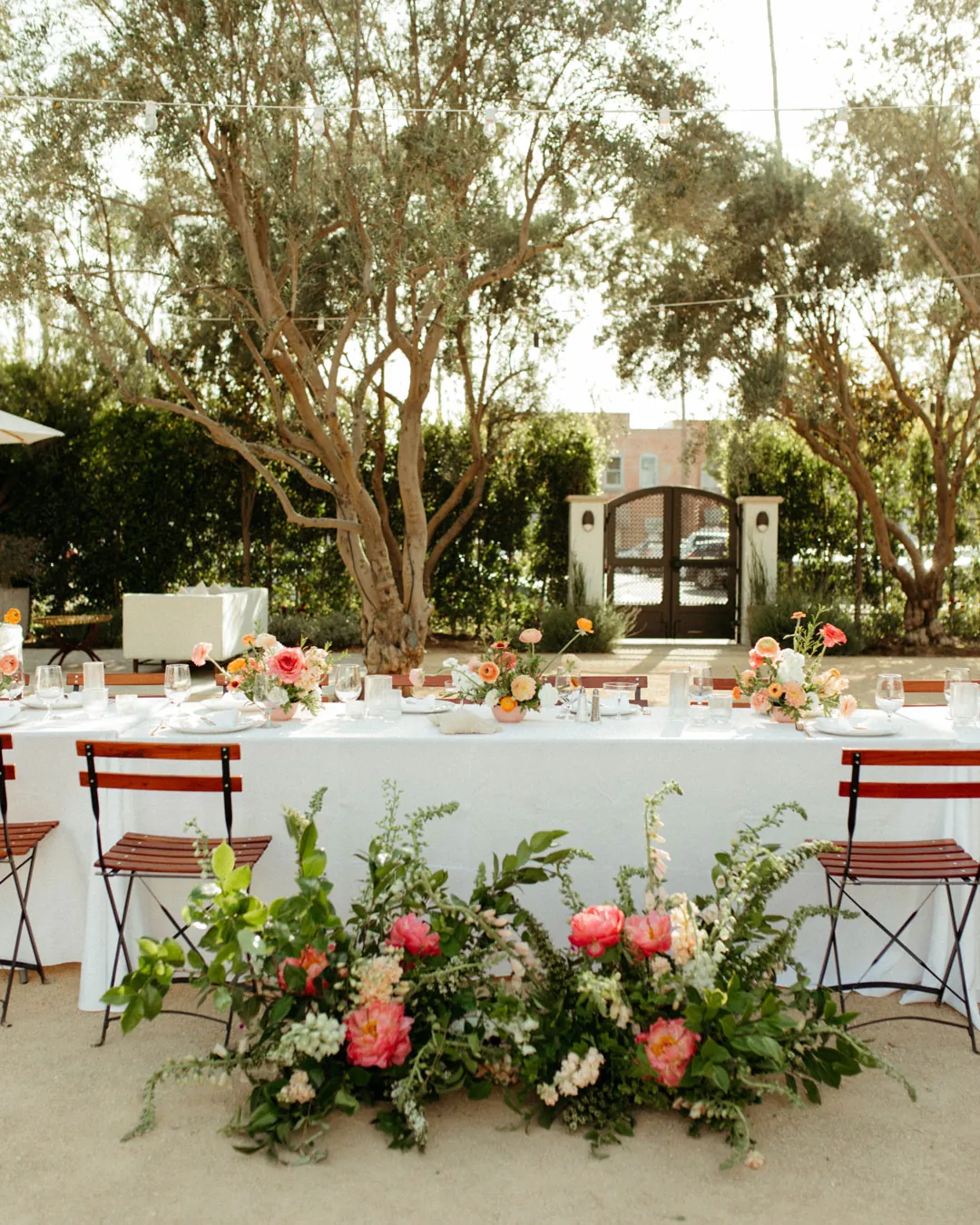 Outdoor sweetheart table surrounded by colorful flowers