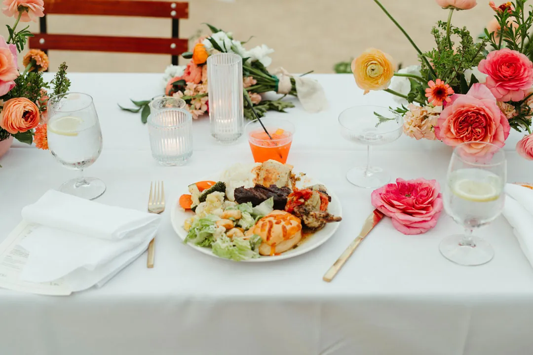 Plated meal beside colorful flowers and candles