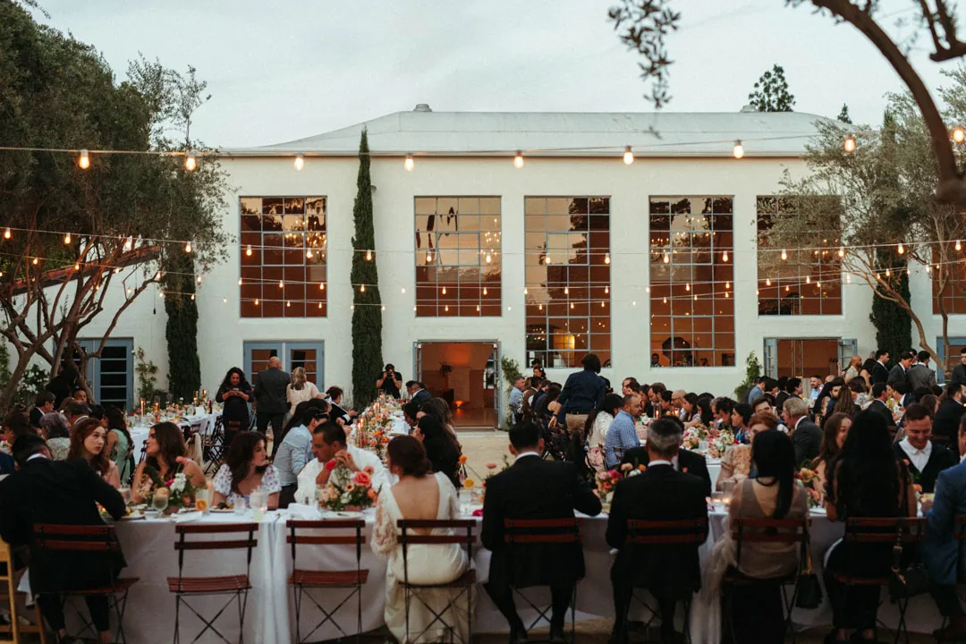 Courtyard guests dining outside the illuminated reception hall