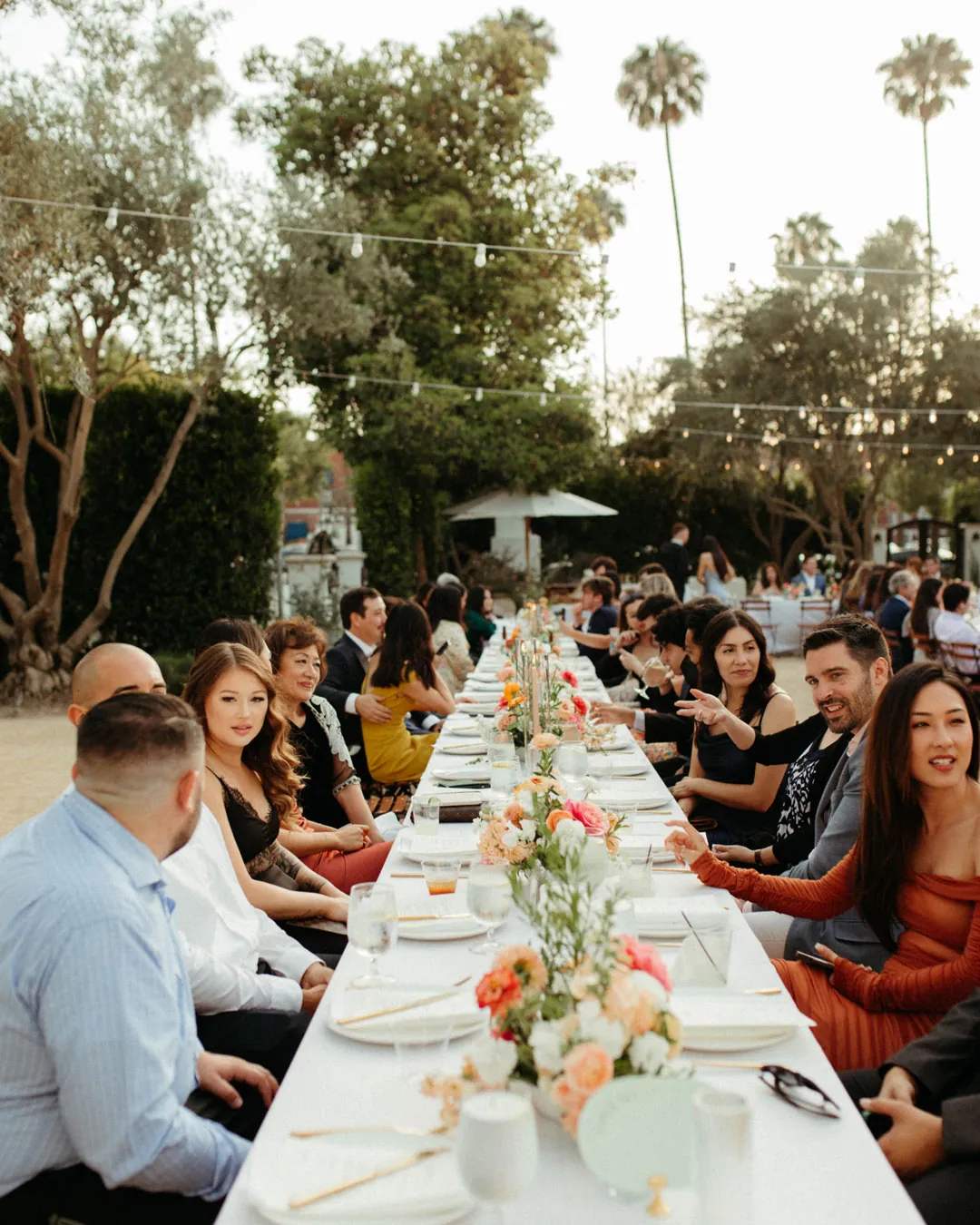 Guests seated along a long flower-decorated table