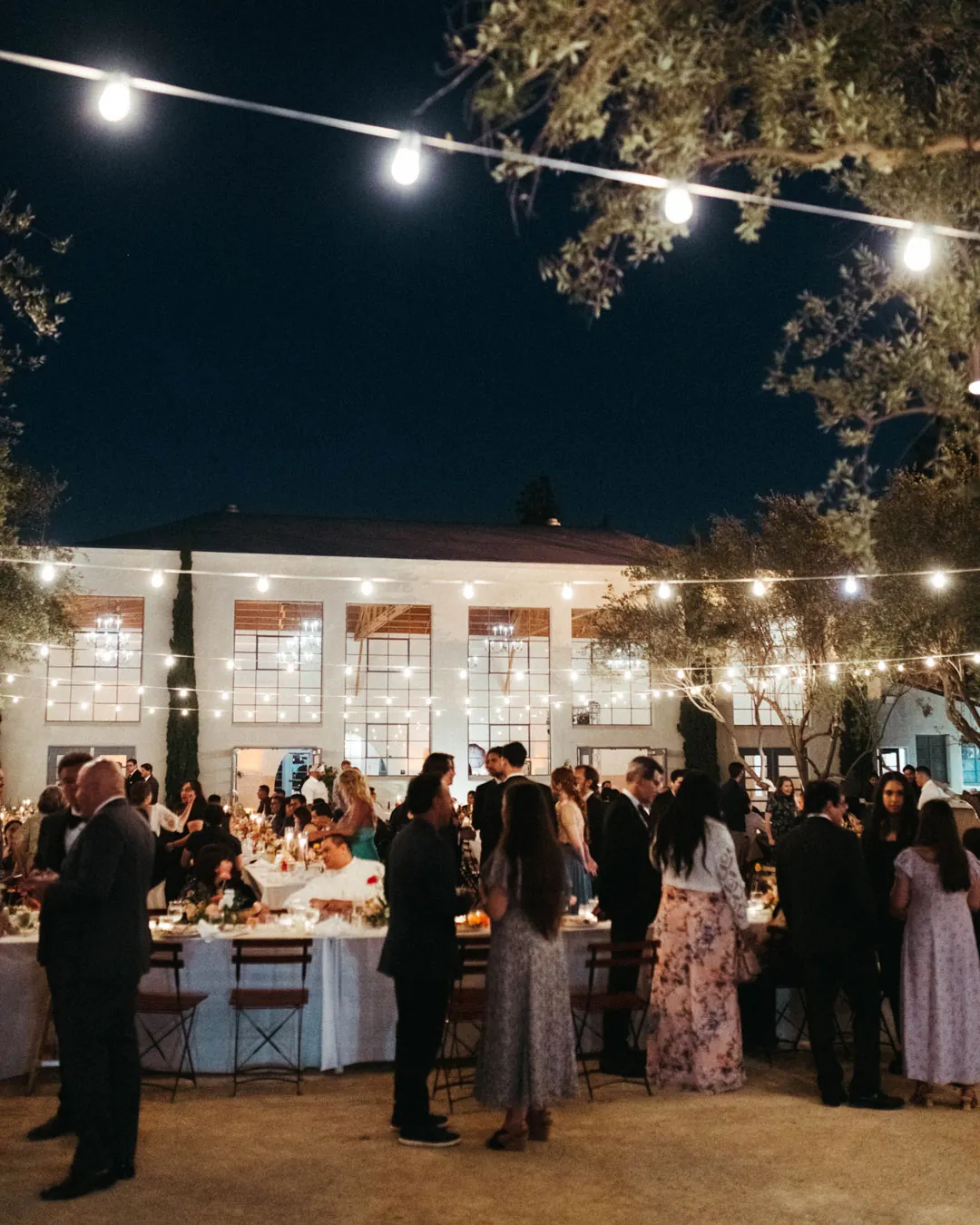 Guests mingling beneath courtyard string lights at night