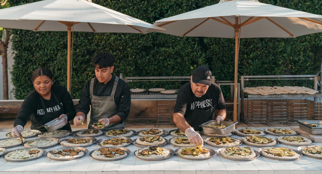 Chefs preparing small plates at an outdoor food station.