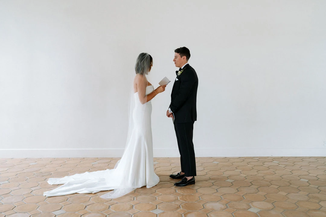Bride touching the groom’s face in a bright room.