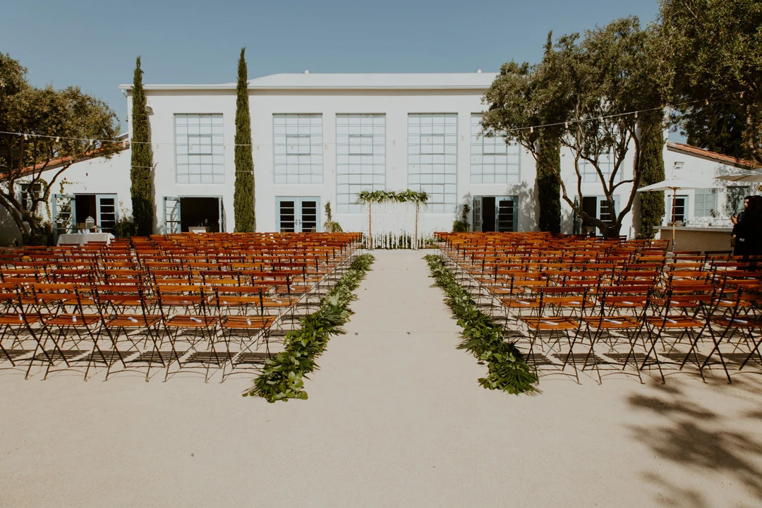 Outdoor ceremony aisle facing the reception hall’s tall windows.