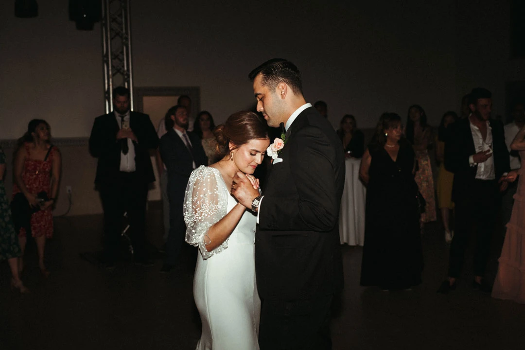Bride and groom dancing among reception guests