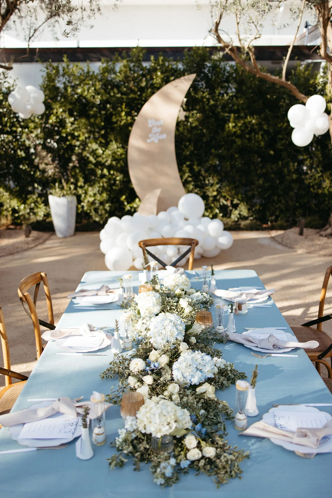 Blue-covered table with flowers and a crescent decoration.