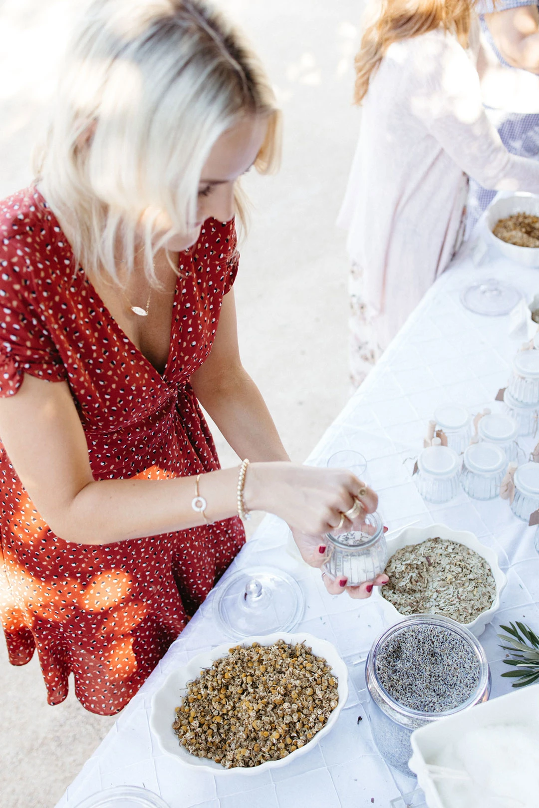 Guest prepares a small container beside bowls of herbs.