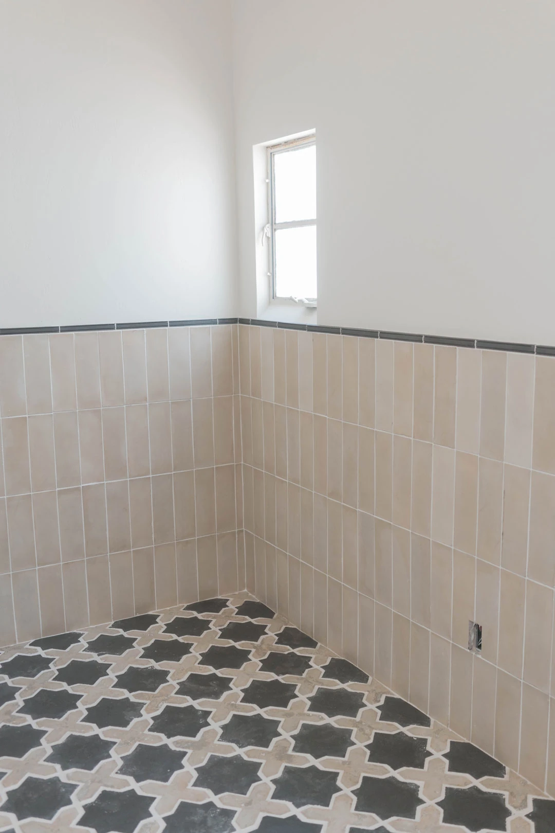 Powder room with patterned floor and tiled walls.