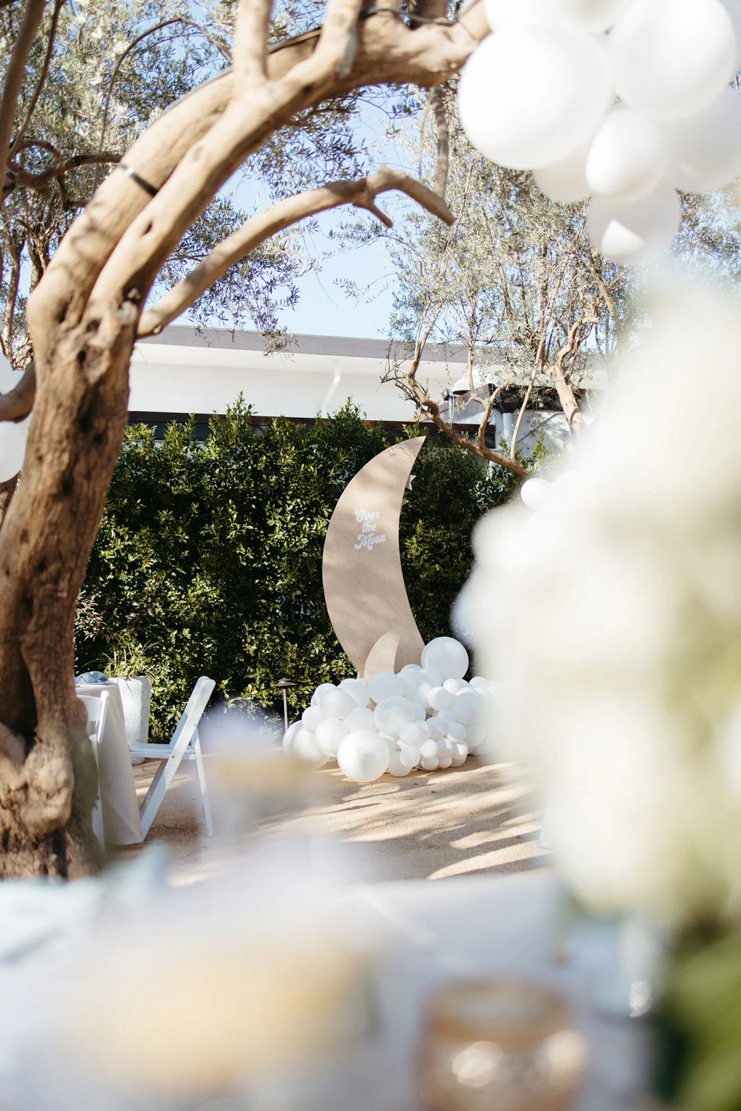 Courtyard table beneath white balloons and a crescent decoration.