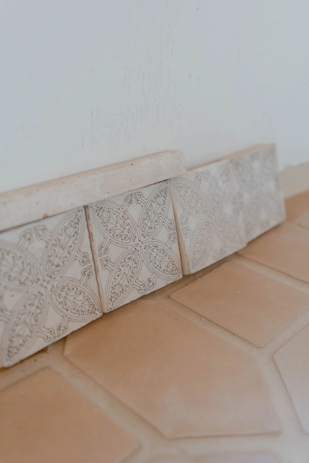 Decorative tile samples rest on a terracotta floor.