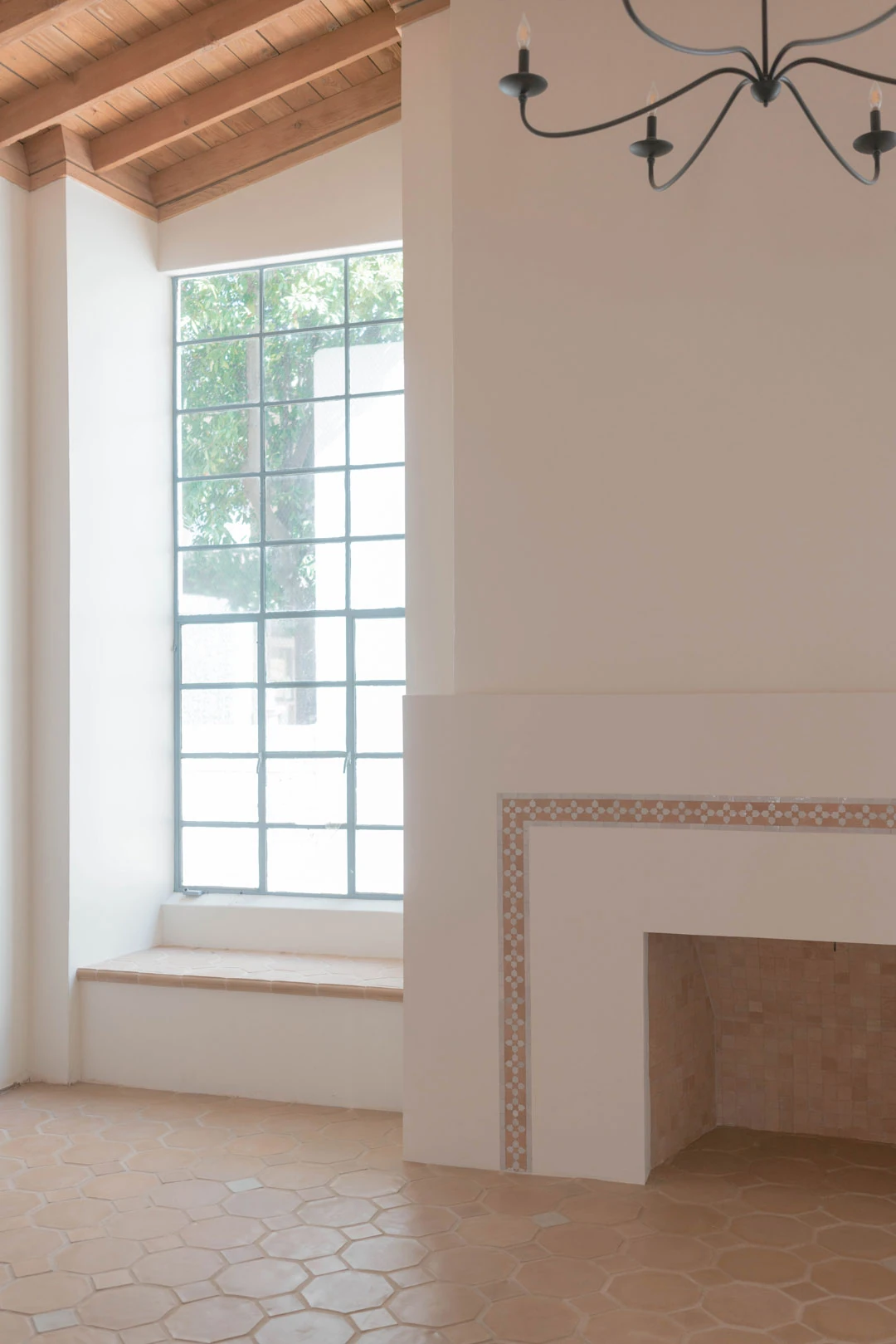 Fireplace beside a tall window in an empty room.