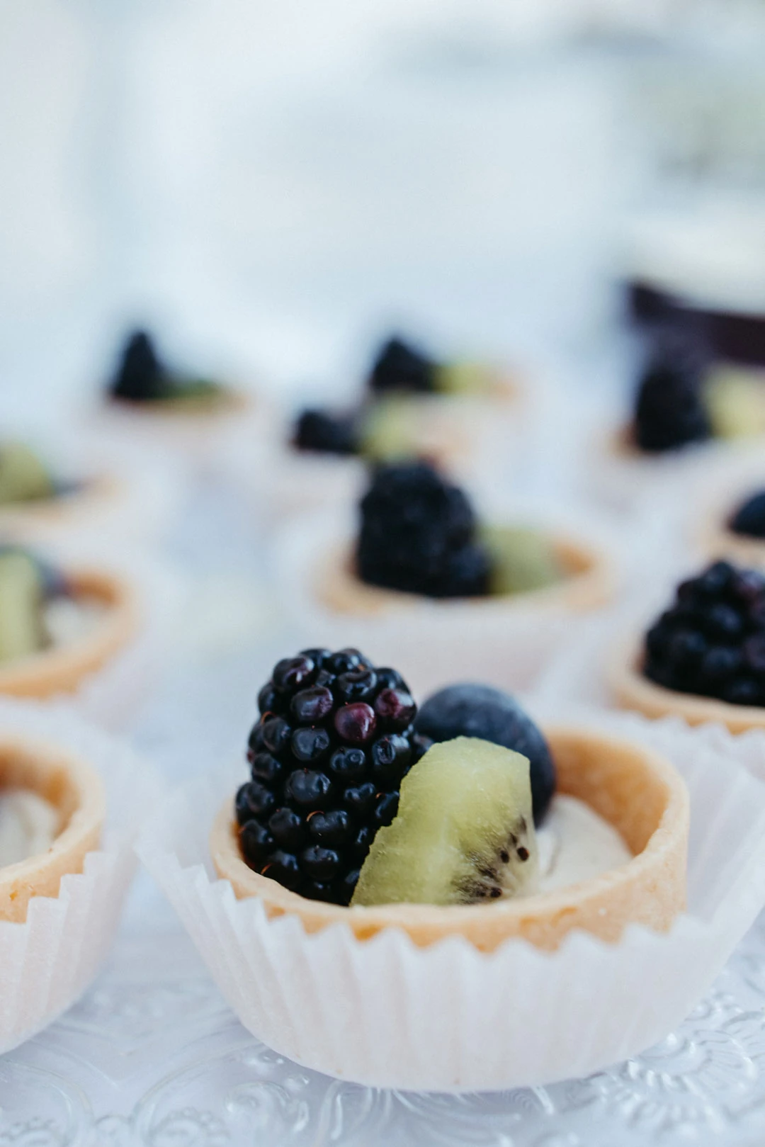 Small fruit tarts topped with blackberries and kiwi.