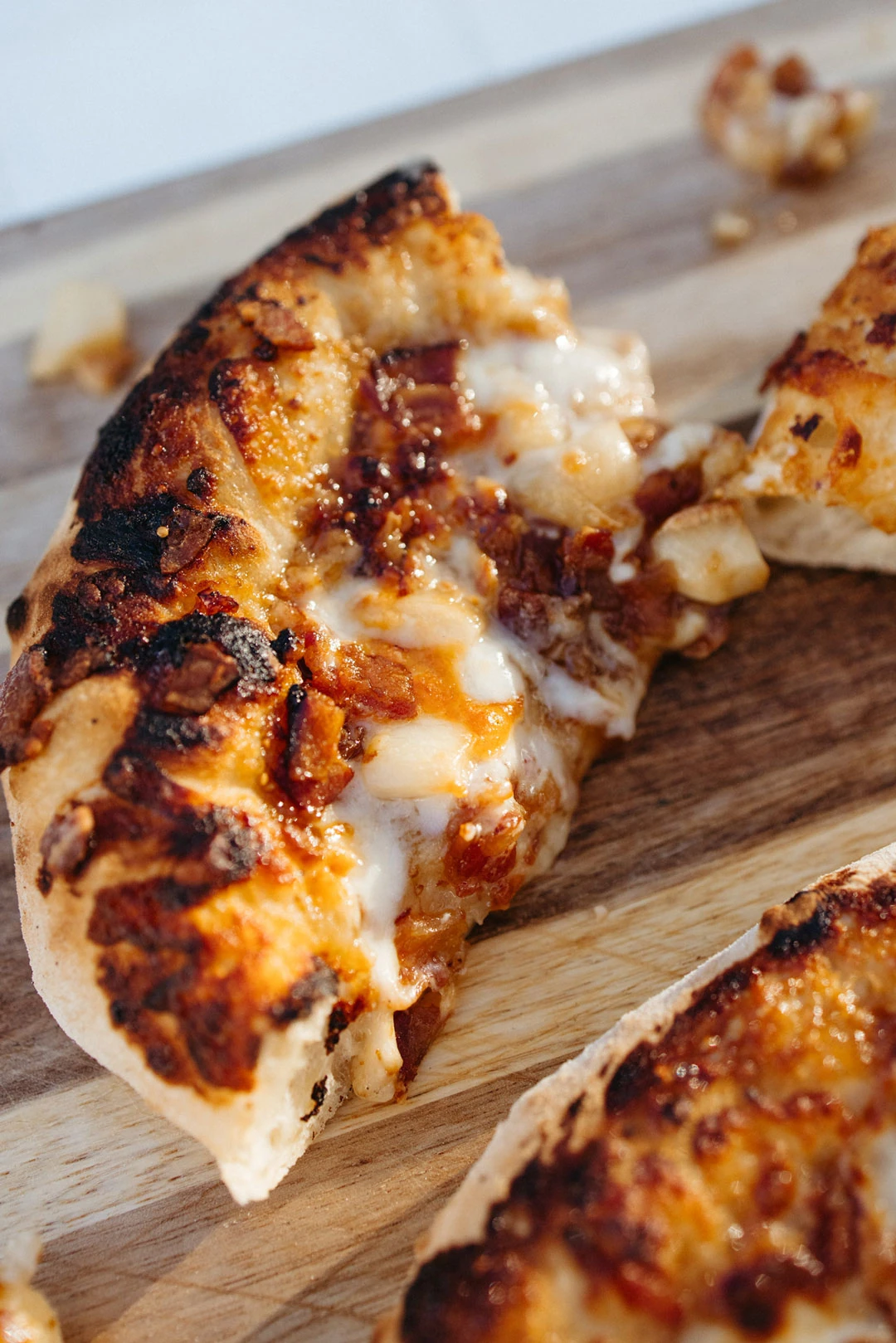 Close view of sliced pizza on a wooden board.