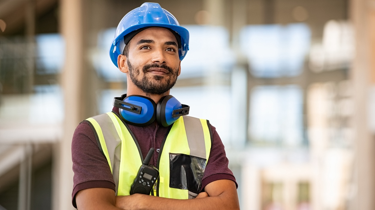 A construction worker wears a hard hat and safety vest.