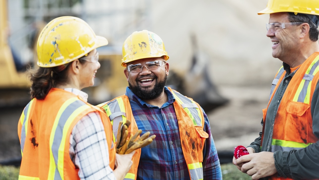 A group of smiling construction workers on a job site.