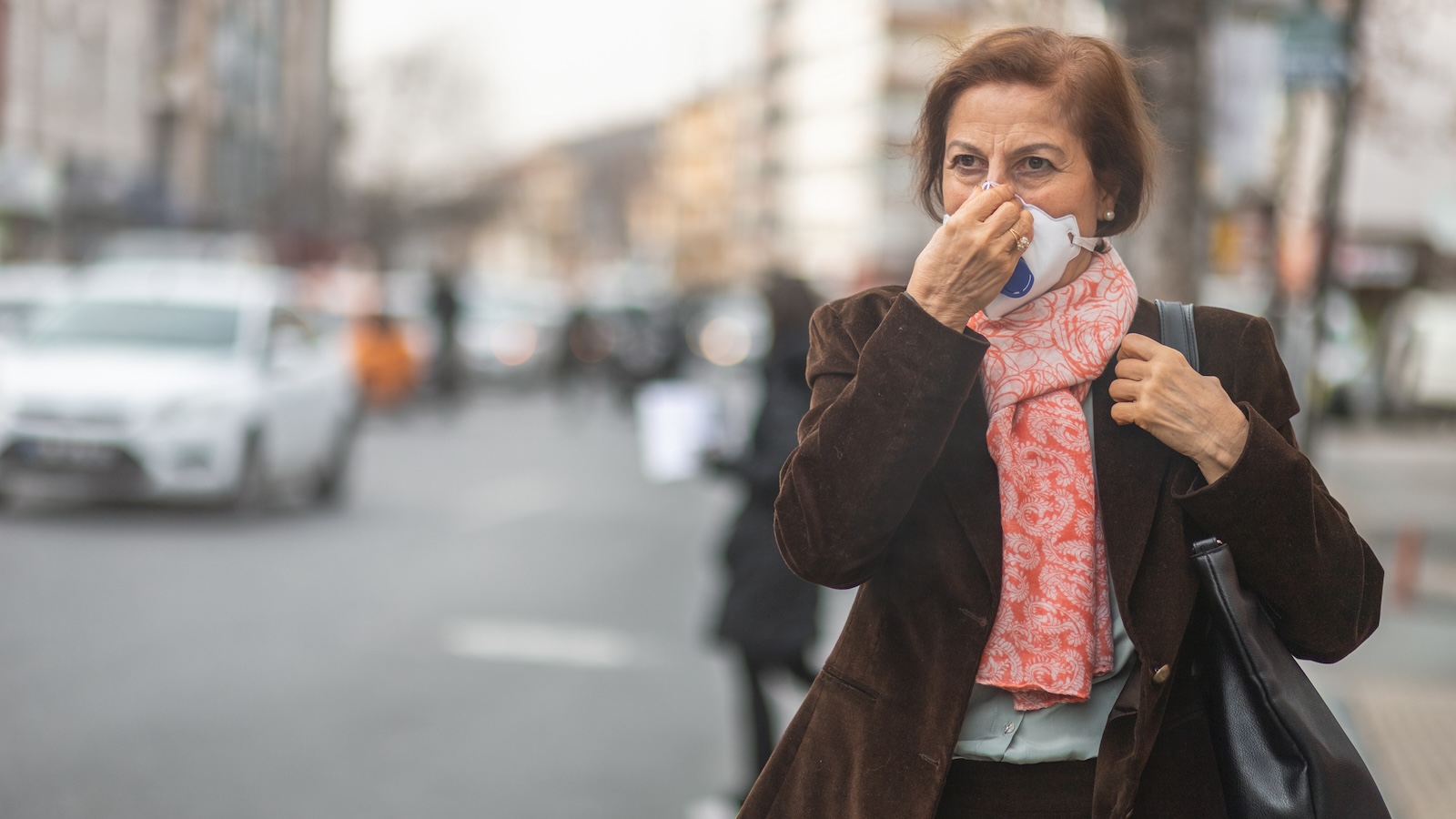 A woman covers her face with a mask due to wildfire smoke permeating the city.