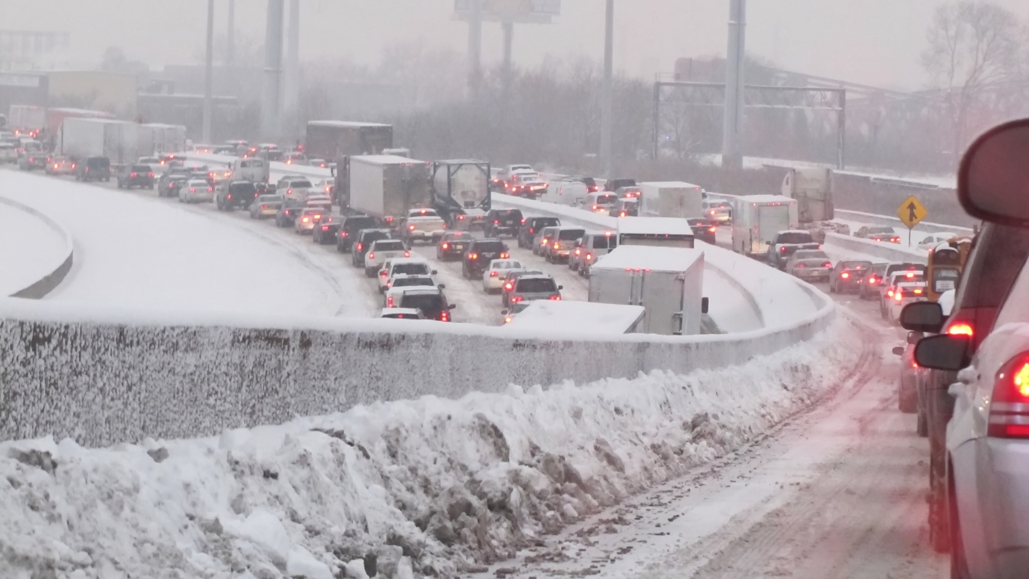 Commuters stuck on the on-ramp to an interstate highway during a Midwestern winter blizzard.