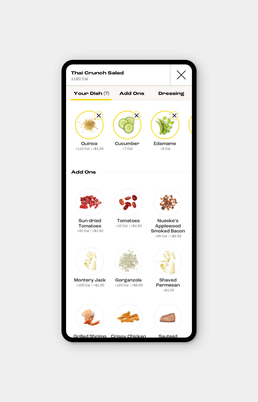Mobile app screen showing customizable Thai Crunch Salad with selected ingredients quinoa, cucumber, and edamame, plus a list of add-ons including sun-dried tomatoes, tomatoes, smoked bacon, cheeses, shrimp, crispy chicken, and sauteed salmon with calorie and price details.