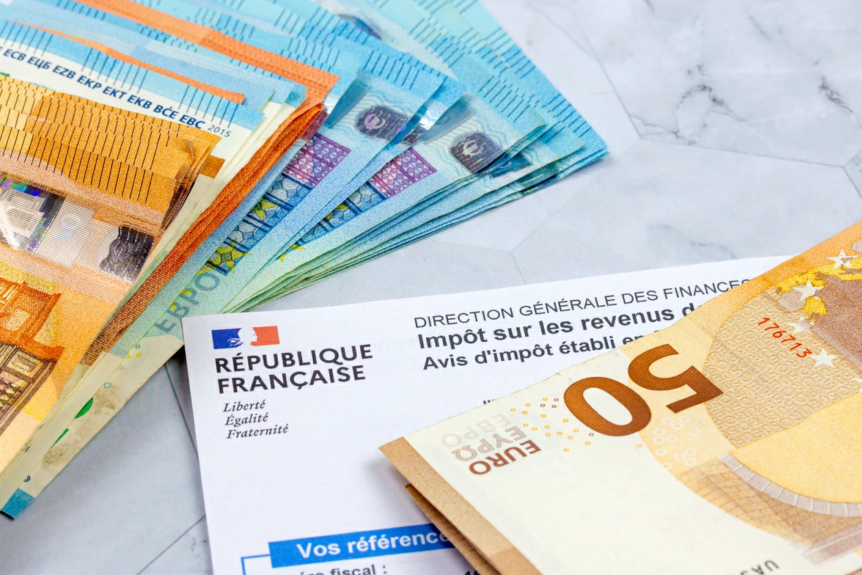 Des liasses d'argent en euro et un formulaire de paiement d'impôt.