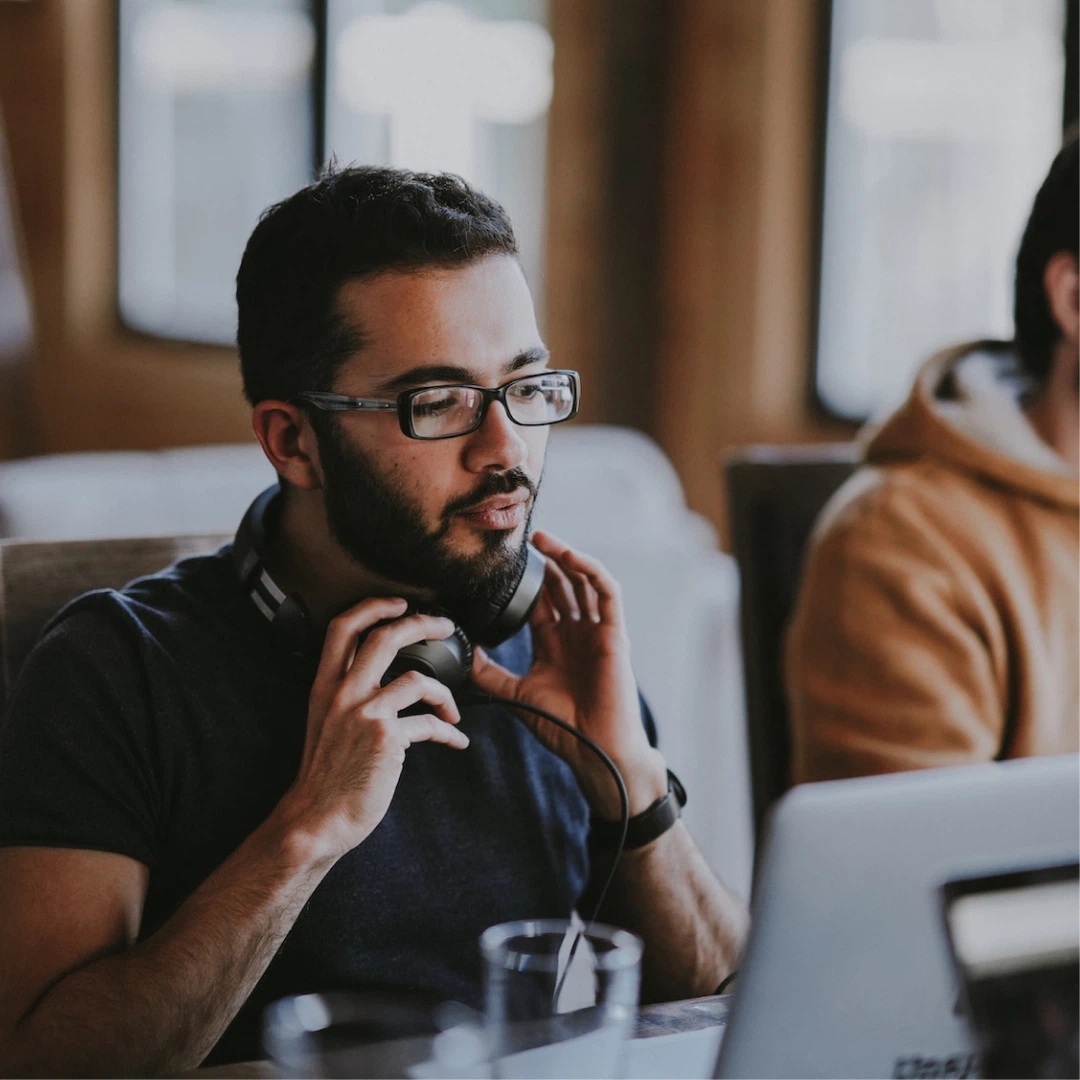 A man sitting a desk with headphones in his hands