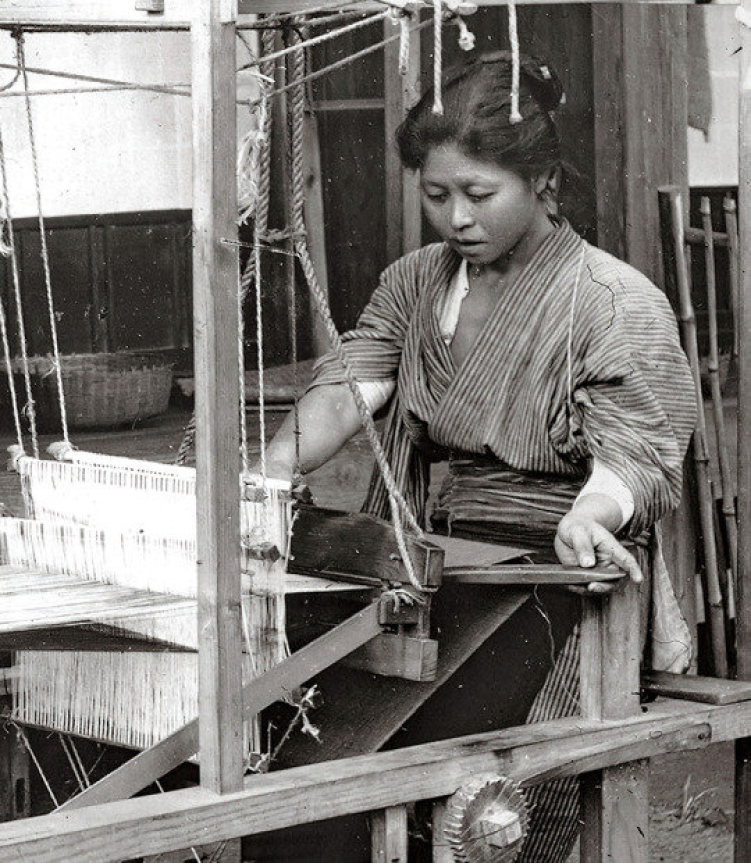 Woman weaving fabric on traditional loom in black and white photograph