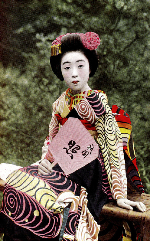 Traditional geisha in colorful kimono with pink floral hair ornament