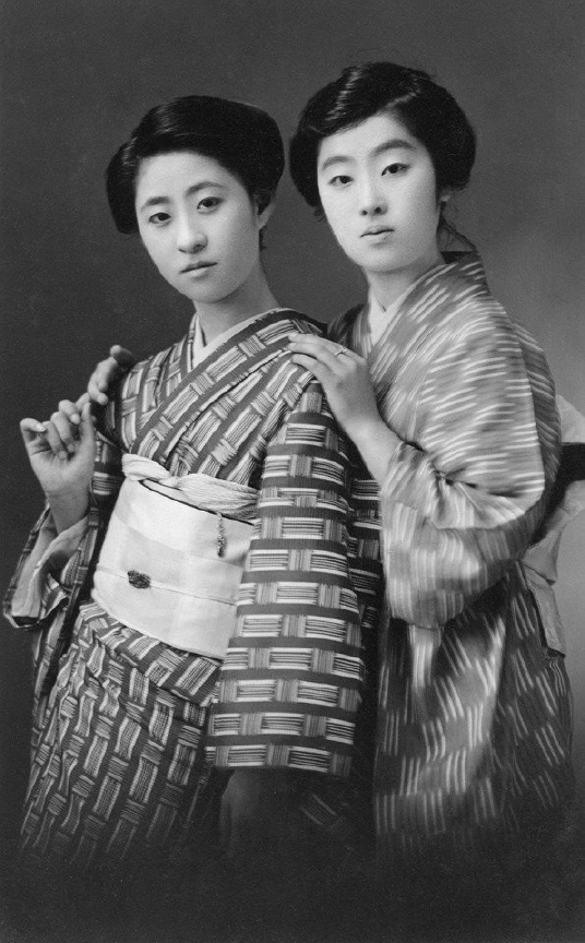 Two women in traditional Japanese kimonos posing together in black and white