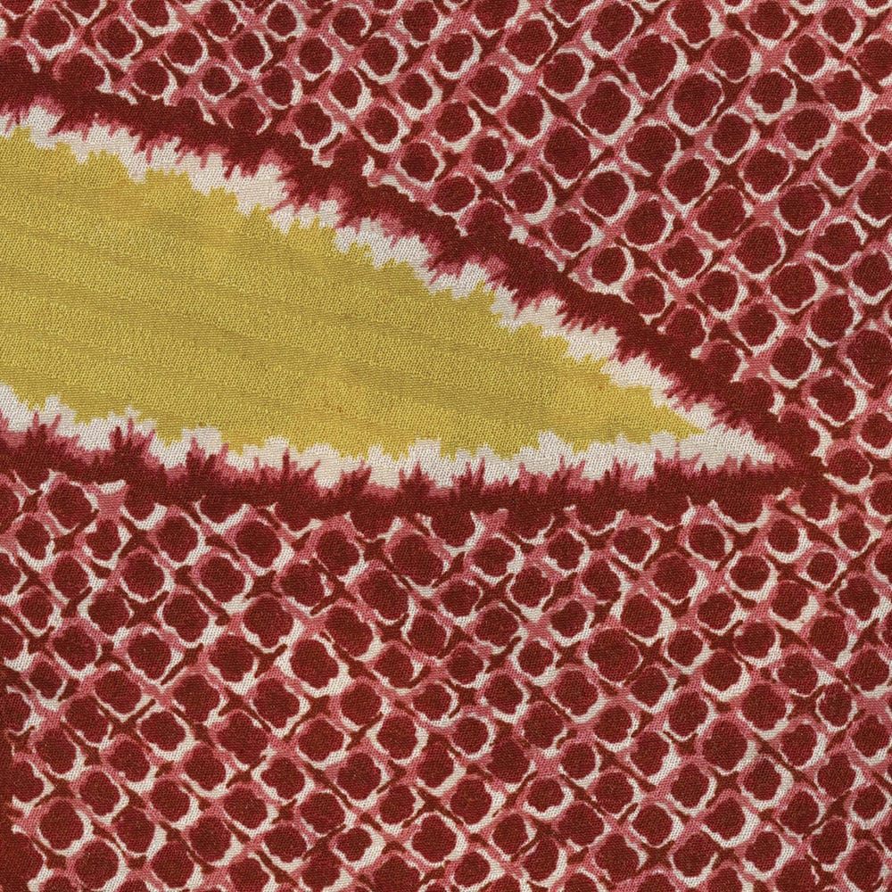 Red and yellow tie-dye fabric with intricate honeycomb-like pattern