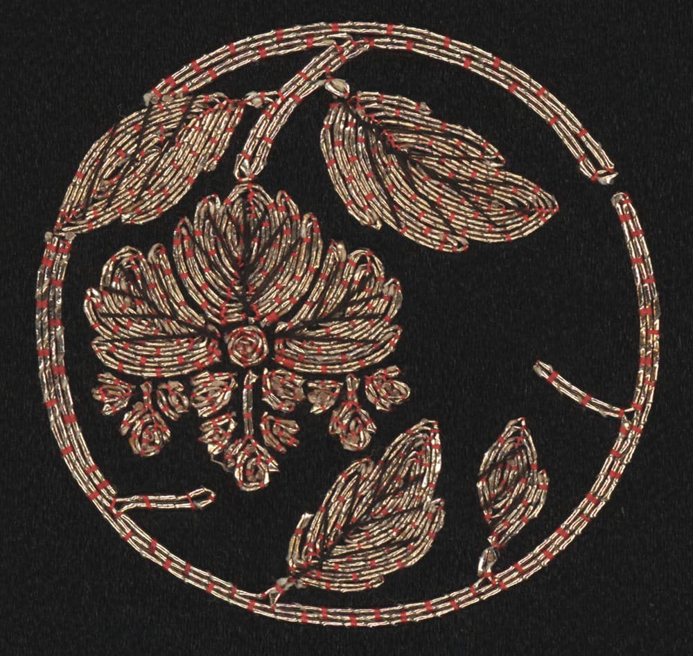 Embroidered floral design with gold and red threads on black background