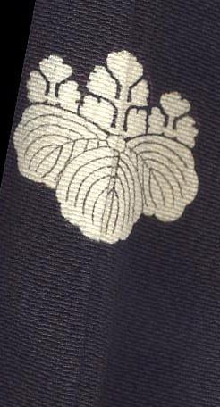 Cream-colored traditional Japanese family crest embroidered on dark textile