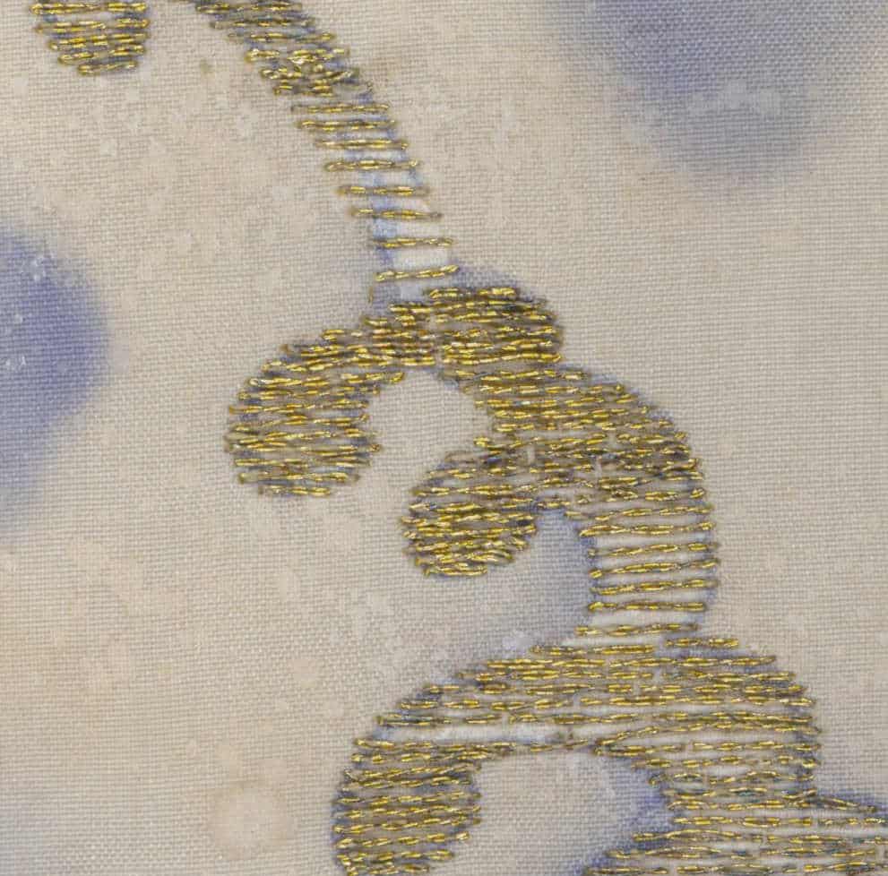 Golden embroidered footprints on soft textile with blue-gray background