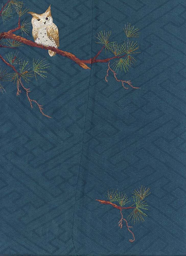 White owl perched on red branch with pine needles against blue background