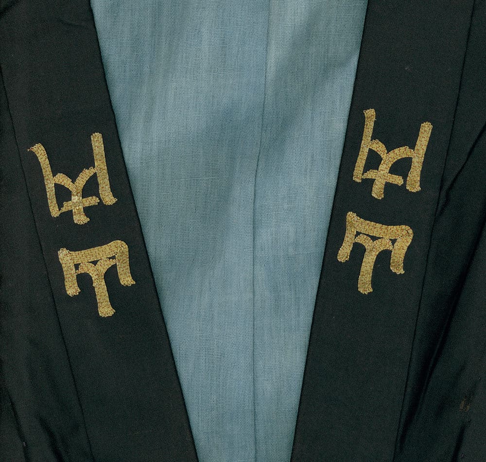 Gold embroidered symbols on dark green and light blue fabric