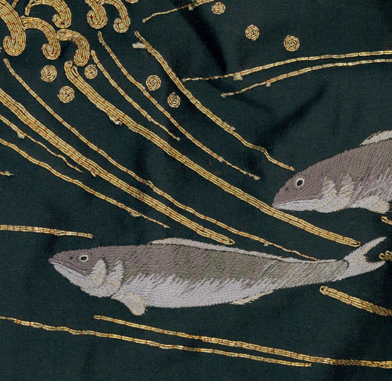 Embroidered gray fish swimming among golden threads on dark background