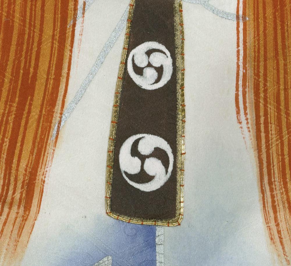 Japanese tomoe symbol on dark textile with ornate golden border