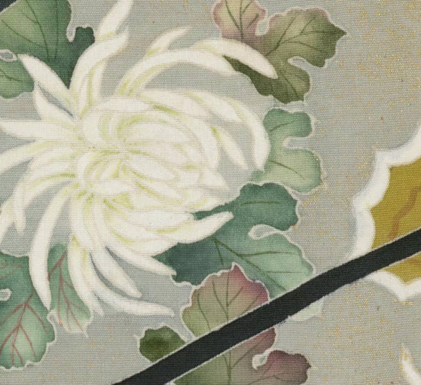 Delicate white chrysanthemum with green leaves on textured fabric