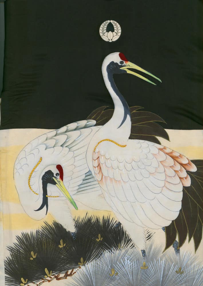 Two elegant Japanese cranes with red heads against dark green background