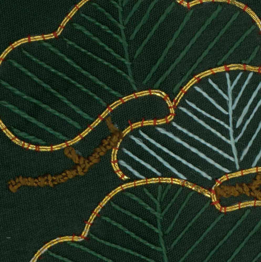 Gold-threaded embroidery on dark green fabric with leaf-like patterns